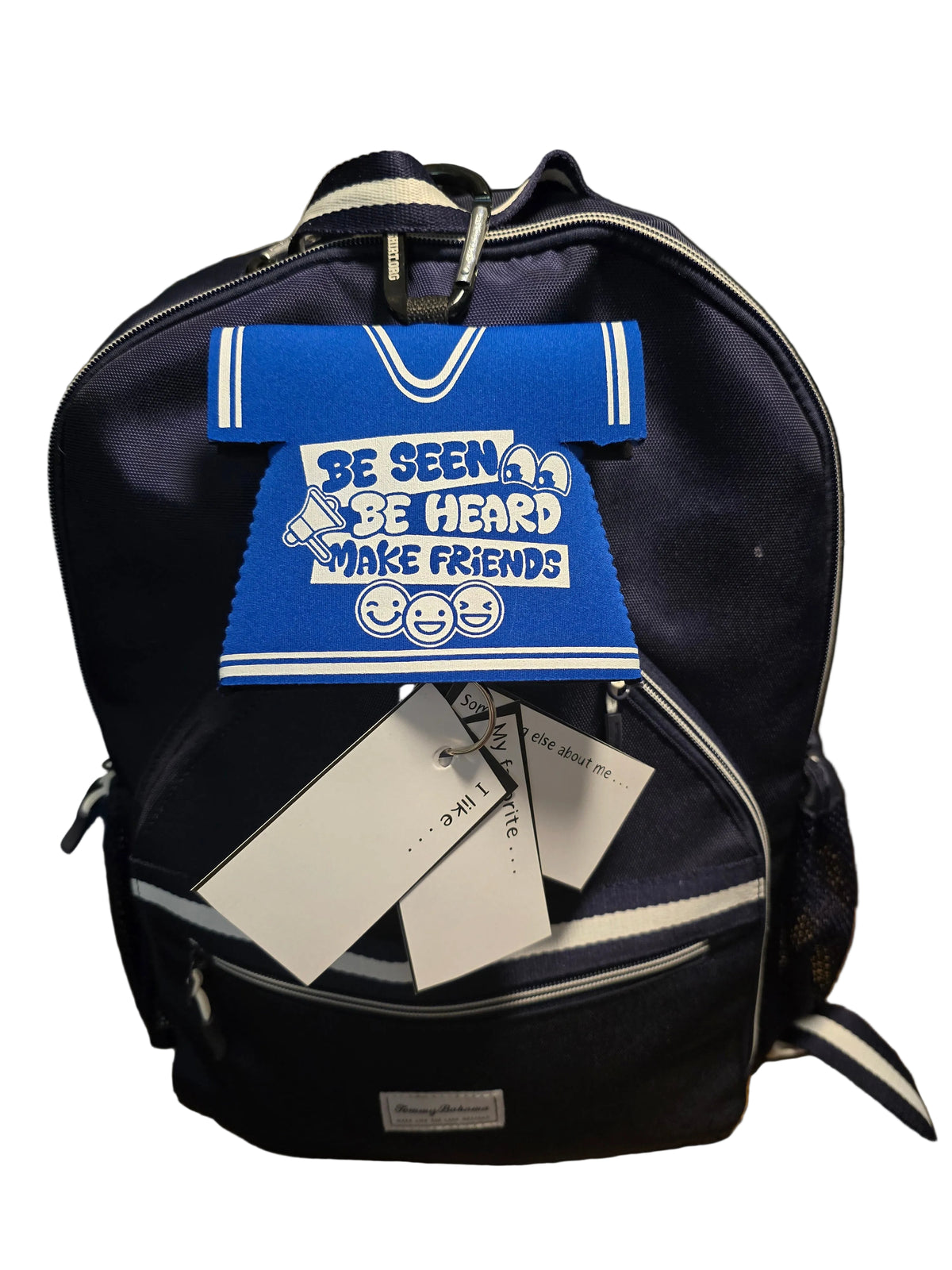 A navy blue backpack with white trim and a blue cheerleader-style front patch that reads 'BE SEEN. BE HEARD.